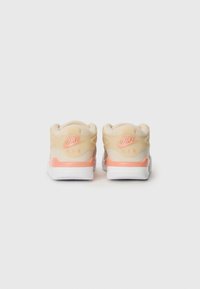Zapatillas Nike Air beige con una textura suave, que presentan un acento rosa suave, suela blanca y un destacado logo "Nike Air" en el talón.