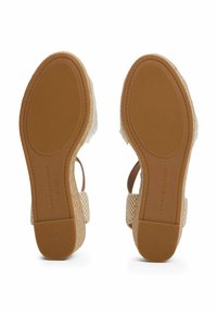 Sandali espadrillas beige con texture intrecciata, suola in gomma e cinturini marroni. Tacco rinforzato e dettagli del marchio sulla suola.