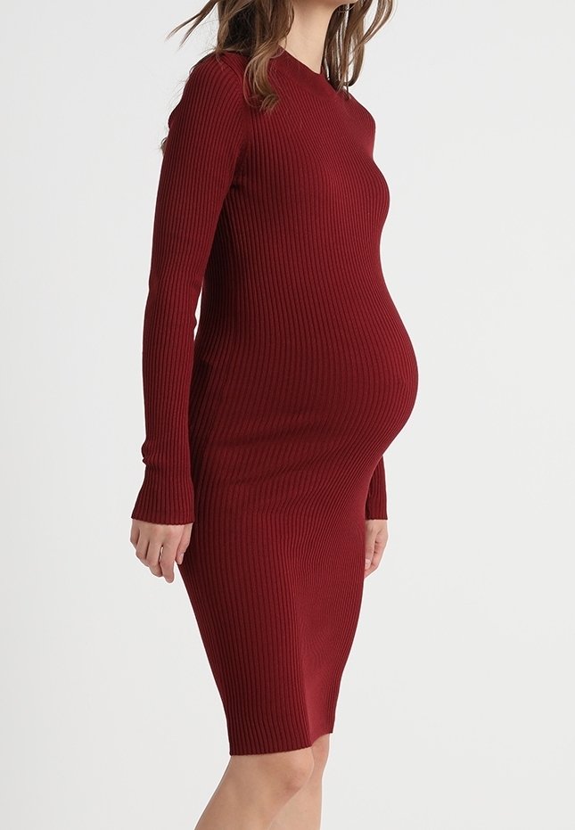 Robe de maternité côtelée bordeaux, à manches longues, silhouette ajustée et longueur au genou avec un tissu texturé.