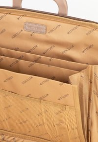 Der Innenraum der tanfarbenen Stofftasche verfügt über mehrere Fächeranordnungen, Netzabschnitte und ein wiederholendes Markenmuster. Glatte Textur mit robuster Konstruktion.