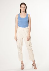 Lyseblå ribbede tank top sammen med cremefarvede cargo-bukser med sidelommer, skræddersyet pasform og beige strop sandaler.