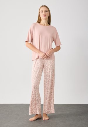 Lys rosa kortærmet top parret med brede bukser med en beige leopardprint. Glat tekstur, afslappet pasform og gulvlængde.