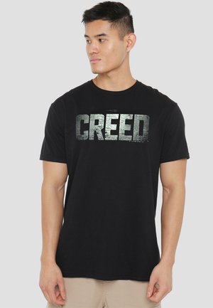 Black cotton t-shirt featuring a large silver "CREED" print across the front. Short sleeves and a classic crew neck design.
