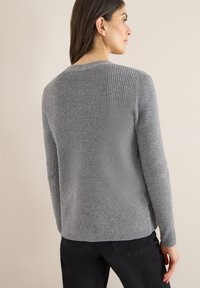 Szary sweter z prążkowanego dzianiny, z długimi rękawami, okrągłym dekoltem i miękką fakturą. Charakteryzuje się lekko zakrzywionym dołem oraz minimalistycznym designem.