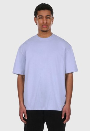 Lys lilla oversized t-skjorte med korte ermer, rund halsutskjæring og lett tekstur. Inkluderer en liten logotag på kanten.