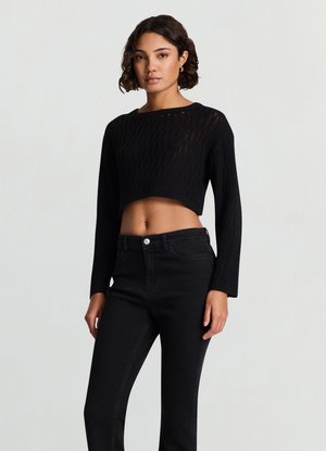 Schwarzer, kurz geschnittener Pullover mit einer strukturierten Strickoptik, langen Ärmeln und einem breiten Rundhalsausschnitt, kombiniert mit hochtaillierten schwarzen Jeans.