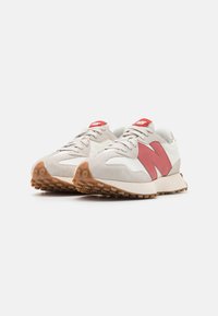 Ein Paar beiger und weißer Sneaker mit roten "N"-Logos, Gummisohlen und Schnürsenkeln, nebeneinander auf einem weißen Hintergrund positioniert.