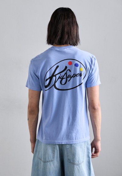 T-shirt di cotone azzurro chiaro con logo circolare nero con accenti rossi, viola e gialli, stampato sul retro. Maniche corte, vestibilità rilassata.