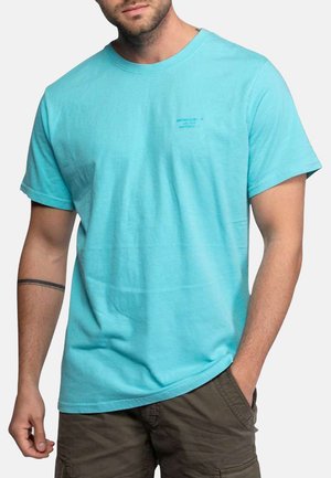 T-shirt turquoise à manches courtes en coton. Présente une coupe légèrement ample et un petit logo bleu imprimé sur la partie gauche de la poitrine.