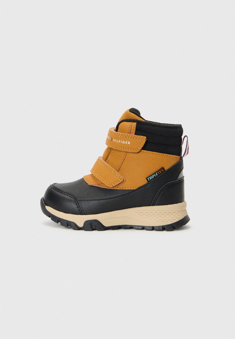 Botas de tobillo negras y naranjas con dos cintas de Velcro, cuero texturizado, suela resistente y un collarín acolchado para comodidad y soporte.