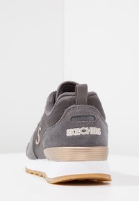 Sneaker grigia con tomaia in suede e dettagli in rete. Presenta un colletto imbottito, un logo e una suola in gomma bianca e gum.