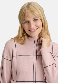 Rosa Pullover mit schwarzem Karomuster, hohem Kragen und langen Ärmeln. Weicher Stoff, gerippte Bündchen und lockere Passform.
