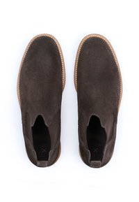 Brune ruskinds slip-on sko med en glat tekstur, rund tå og kontrasterende syninger på en letbrun sål.