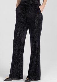 Czarne spodnie o szerokich nogawkach wykonane z miękkiego, teksturowanego materiału z połyskującym wzorem. Posiadają boczne kieszenie oraz gładki pas.