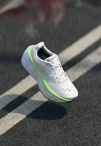 White running shoe with green accents, lightweight design, breathable mesh upper, and textured sole with "FRESH FOAM" branding.