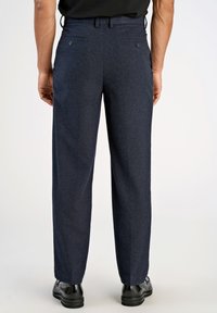 Calças de lã misturada em azul-marinho com um design de perna reta, apresentando dois bolsos traseiros e botões discretos. Acompanhadas por sapatos pretos.