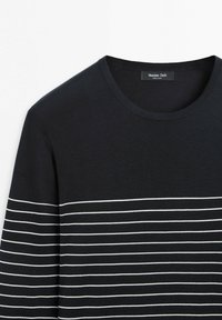 Sort rundhalset sweater med tynde hvide horisontale striber på tværs af bryst og ærmer, mærket Massimo Dutti.