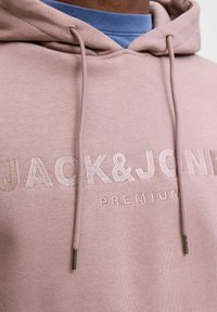 Rosa Sweatshirt mit Kapuze, mit gesticktem "JACK&JONES PREMIUM"-Text. Glatte Textur und verstellbare Kordeln mit metallenen Spitzen.