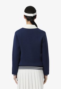 Maglione blu navy con colletto bianco e orlo a righe. Tessuto morbido, maniche lunghe e design semplice, modellato per un look aderente.