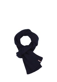 Écharpe tricotée bleu marine pliée en boucle avec une petite étiquette rectangulaire portant des rayures blanches, brunes et noires.