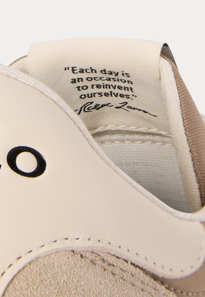 Skoinnerdel som visar ett sött citat på tungan: "Varje dag är ett tillfälle att återskapa oss själva," med beige och tan-färgade läder- och tygdetaljer.