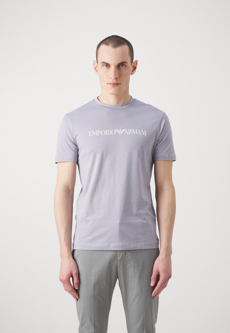 Hele lilla puuvillane T-särk, millel on ümar kaelus ja lühikesed varrukad, valge "Emporio Armani" logo rinnal.