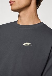 Grå sweatshirt med rund halsudskæring, med et lille hvidt Nike-logo på brystet. Fremstillet af glat, blødt stof med en klassisk pasform.
