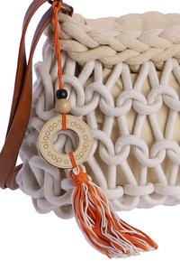 Bolso de macramé tejido beige con borde trenzado, correa de cuero, cuentas de madera, etiqueta circular y borla naranja y blanca.