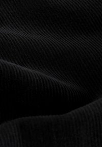 Tessuto in corduroy nero che presenta una ribattuta distintiva, con fibre morbide e pelose che creano onde sottili su tutto il materiale.