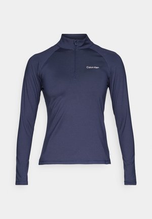 Tricou cu mânecă lungă navy, cu fermoar, realizat dintr-un material ușor, având un guler înalt și mâneci raglan, cu un mic logo alb pe piept.