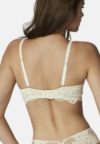 Lace bralette in ivoor met verstelbare bandjes, bloemenpatroon, gegolfde randen en een haak-en-oogsluiting aan de achterkant.