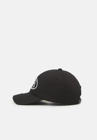 Căciulă de baseball neagră cu brăcină curbată, având un logo circular pe partea din față. Fabricată din material textil cu detalii de cusătură. Curea de ajustare la spate.