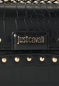 Crna kožna torbica s reljefom krokodila, detalji s zlatnim zakovicama i metalnom pločicom s logotipom Just Cavalli.