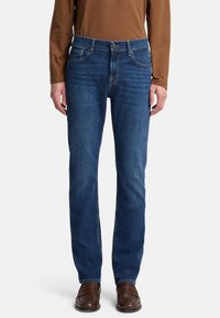 Granatowe dżinsy o prostym kroju nogawki, z przednimi kieszeniami, zapinane na guzik, z delikatnym wyblakłym wykończeniem na udach.