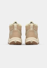 Beige Wanderschuhe aus einer Mischung aus Wildleder und Stoff, mit einer robusten Sohle, gepolstertem Absatz und einem GORE-TEX-Logo an der Seite.