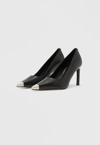 Czarne skórzane buty na wysokim obcasie z zakończeniem w kształcie ostrego czubka oraz metaliczną, srebrną nakładką na palcach. Gładka tekstura i smukły obcas typu szpilka.