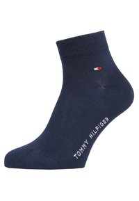 Chaussette en coton marine avec un poignet côtelé, arborant un petit logo rouge et blanc sur le côté et le texte "TOMMY HILFIGER" en blanc.