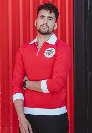 Rode langemouw polo met een ritskraag, witte kraag en manchetten. Heeft een clubembleem op de borst. Gladde textuur, slim fit ontwerp.