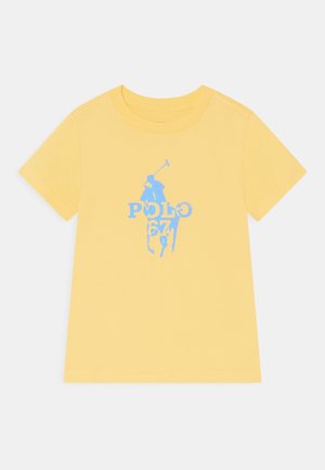 Camiseta amarilla de manga corta con gráfico de jugador de polo azul y texto "POLO 67" centrado en el pecho.