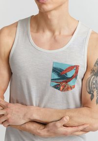 Top basic din material gri deschis; prezintă o ieșire albastră cu un imprimeu de pasăre tropicală; textură moale, design slim fit.