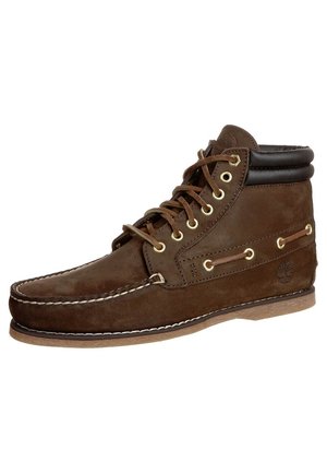 Bota casual de cuero marrón de caña alta con cordones en el frente, cuello acolchado, costura en la punta tipo mocasín y suela de goma, logotipo de Timberland grabado en el talón.