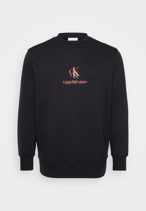 Svart hettegenser med rund hals, lange ermer, ribbestrikkede mansjetter og et midtlogo-design i rødt og hvitt som leser "Calvin Klein Jeans."