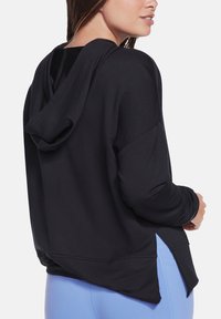 Schwarzer Hoodie, lockere Passform, seitliche Schlitze am Saum und weicher Stoff. Hintergrund ist reinweiß. Keine sichtbaren Beschläge oder Verzierungen.