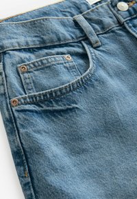 Světle modré džíny mají klasický střih, kontrastní šití a malou zadní kapsu zvýrazněnou bronzovými prvky.