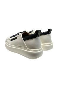 Sneakers bianchi in pelle con suola in gomma spessa, accenti blu navy sulla linguetta e sul tallone, e lacci neri. Presentano un marchio sul lato.