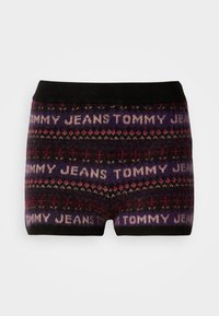 Pletene kratke hlače s tamnom podlogom i ponavljajućim uzorkom teksta "Tommy Jeans" u bijeloj i svijetlo ružičastoj boji, naglašene geometrijskim dizajnima.