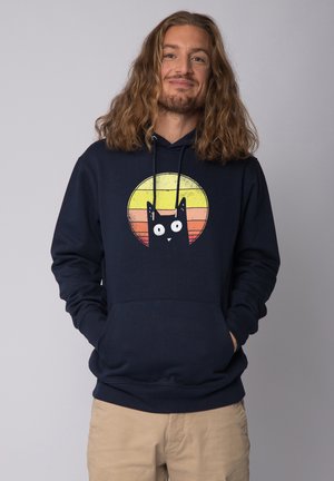 Marineblauwe hoodie met een voorzak, featuring een grafiek van een kat tegen een gradient cirkel in geel, oranje en rood.