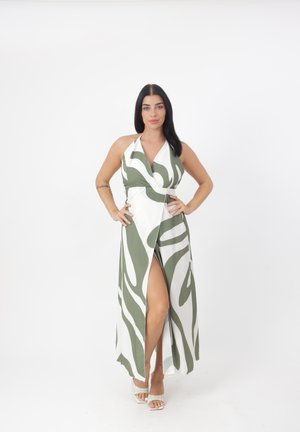 Robe maxi blanche avec des rayures ondulées vertes, design à col halter. Elle présente une fente haute, une texture lisse et un tissu fluide.