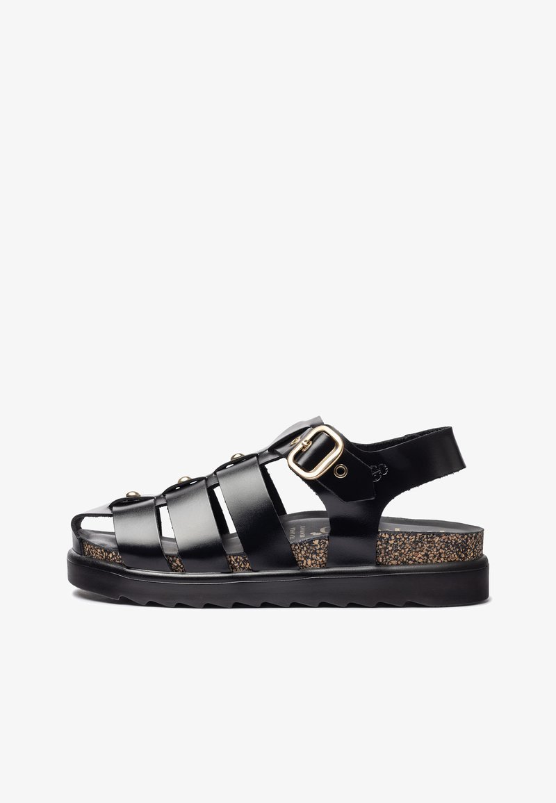 Black strappy sandal with a glossy finish, featuring a buckle accent, cork insole, and textured black outsole. Open-toe design.
