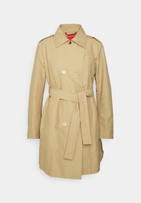 Beżowy trencz wykonany z lekkiego materiału, z podwójnym zapięciem z przodu, dwoma dużymi guzikami, paskiem w talii i klasycznym kołnierzem.